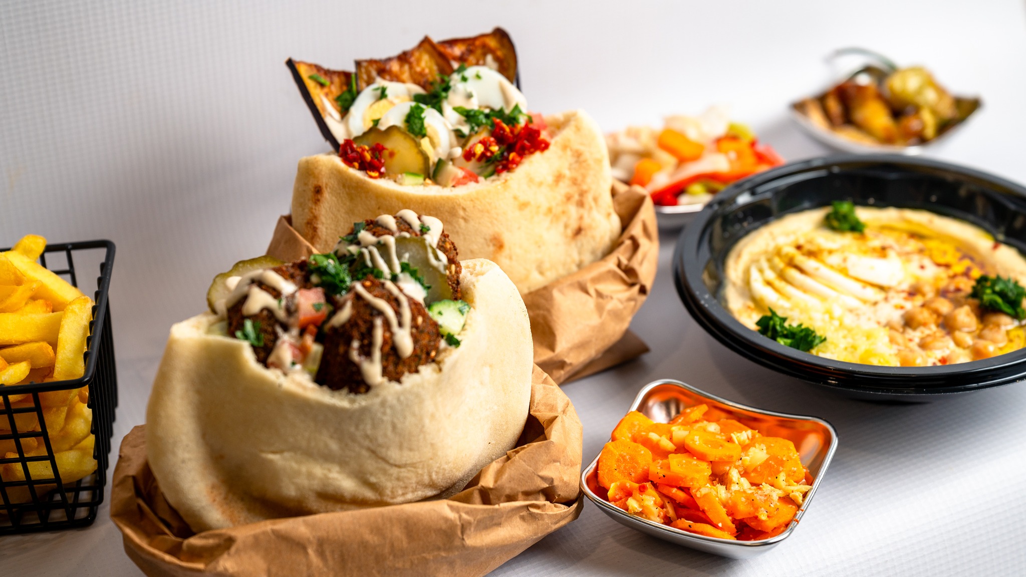 Falafel and sabich pitas with hummus, fries and pickles at Falafel Station Tirana
