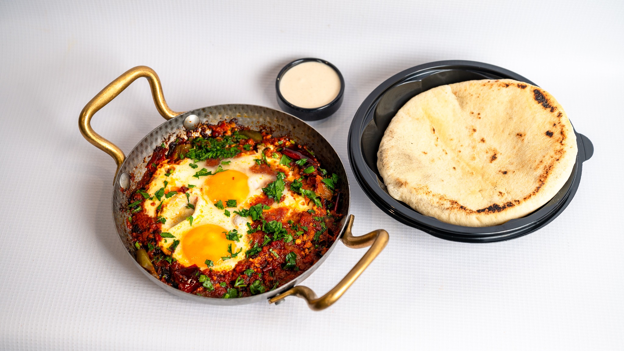 Shakshuka served with pita and tahini
